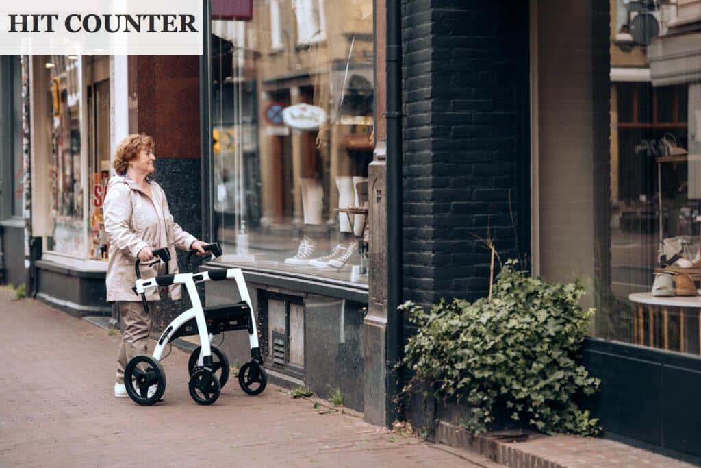 A woman walking with a walker on a sidewalk